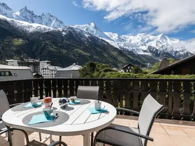 a white table and chairs on a balcony with mountains at Appartement spacieux à Chamonix avec terrasse et parking privé - FR-1-343-173 in Chamonix-Mont-Blanc