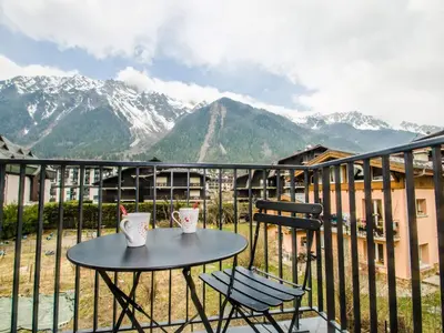 a table and chairs on a balcony with mountains at Appartement chalet à Chamonix avec wifi et parking privé - FR-1-343-201 in Chamonix-Mont-Blanc