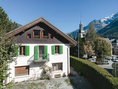a white building with green shutters and a church at Appartement central à Chamonix avec parking et wifi, proche pistes - FR-1-343-194 in Chamonix-Mont-Blanc