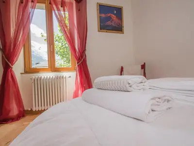 two beds in a room with red curtains and a window at Appartement central à Chamonix avec parking et wifi, proche pistes - FR-1-343-194 in Chamonix-Mont-Blanc