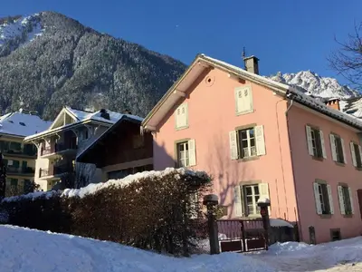 a pink house in the snow with a mountain at Appartement Chamonix 3* - 4 pers. + Animaux admis - FR-1-343-216 in Chamonix-Mont-Blanc