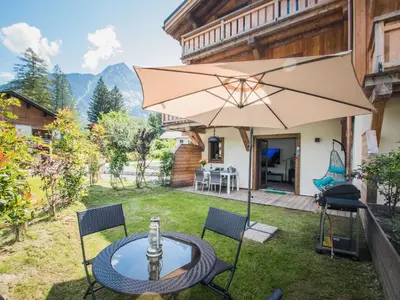 a patio with a table and an umbrella at Bel appartement 3 étoiles aux Praz de Chamonix, près du téléphérique de la Flégère - FR-1-343-213 in Chamonix-Mont-Blanc