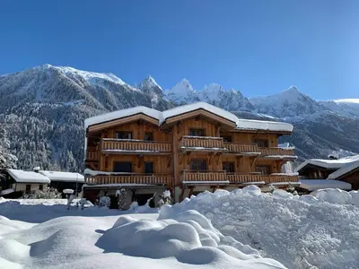 a log cabin in the snow with mountains in the background at Bel appartement 3 étoiles aux Praz de Chamonix, près du téléphérique de la Flégère - FR-1-343-213 in Chamonix-Mont-Blanc