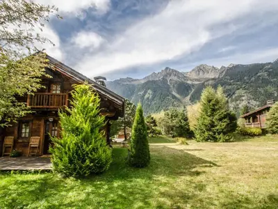 a house in a field with mountains in the background at Charmant mazot avec jardin, animaux admis, parking, wifi - FR-1-343-215 in Chamonix-Mont-Blanc