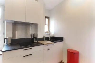 a kitchen with white cabinets and a black counter top at Vallot - Chamonix Centre in Chamonix-Mont-Blanc