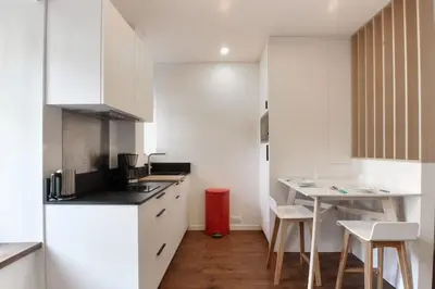 a kitchen with white cabinets and a table and chairs at Vallot - Chamonix Centre in Chamonix-Mont-Blanc