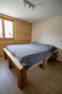 a bedroom with a wooden bed in a room at Le Lac - Servoz - Appartement paisible de 70m² in Les Houches