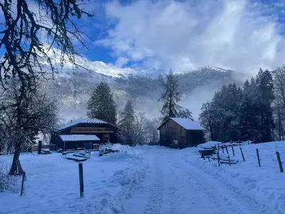 a snow covered field with a barn and mountains at Le Chalet de Bémont in Samoëns