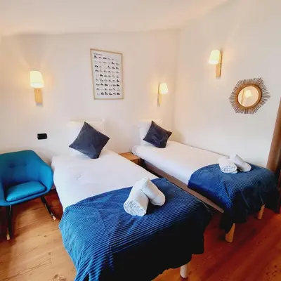 a room with two beds and a blue chair at ALPES IV - Hyper Centre - Parking - 40m² in Chamonix-Mont-Blanc