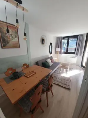 a living room with a table and chairs and a couch at Superbe 2 pièces, centre vue Mont-Blanc avec balcon et parking gratuit in Chamonix-Mont-Blanc