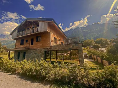 a large wooden house on a hill with a yard at Chalet Amour blanc Chamonix Les Houches in Les Houches