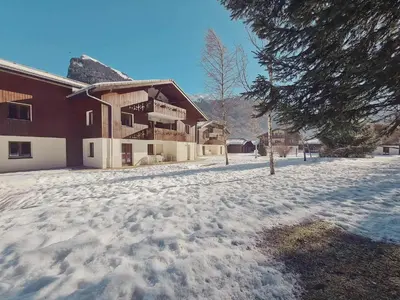 a snow covered yard in front of a building at Appartement lumineux avec piscine et parking près du centre - FR-1-624-125 in Samoëns