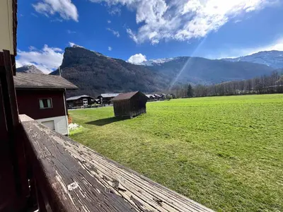 a view of a field with a barn and mountains at Appartement lumineux avec piscine et parking près du centre - FR-1-624-125 in Samoëns