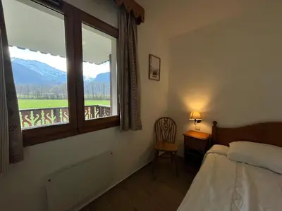 a bedroom with a bed and a window with a view at Appartement lumineux avec piscine et parking près du centre - FR-1-624-125 in Samoëns