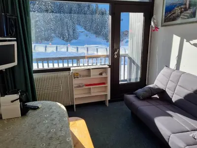 a living room with a couch and a large window at Studio idéal pour l'hiver au pied des pistes - FR-1-687-112 in Arâches-la-Frasse