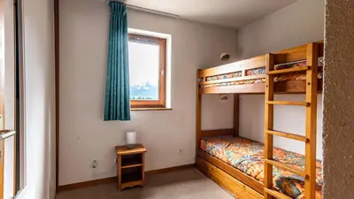 a bedroom with two bunk beds and a window at Les Sitelles - 11 - Piscine Appart 6 pers in Morillon