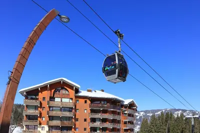 a gondola is being lifted on a ski lift in front of a building at Les Sitelles - 11 - Piscine Appart 6 pers in Morillon