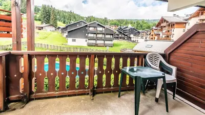 a balcony with a green table and a chair at Les Sitelles - 11 - Piscine Appart 6 pers in Morillon