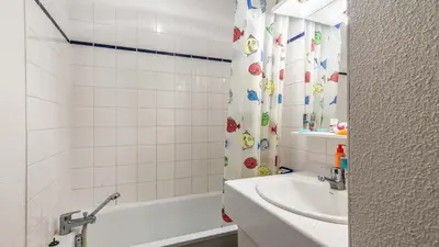 a bathroom with a tub and a sink and a shower curtain at Les Sitelles - 18 - Belle vue Appart 6 pers in Morillon