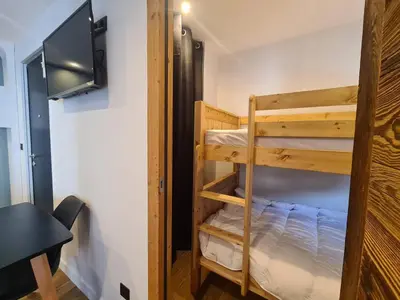 a room with two bunk beds and a tv at Spacieux 2 pièces + cabine, idéal famille, 5 pers, centre village, proche commerces et pistes - FR-1-572-156 in Arâches-la-Frasse