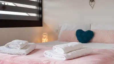 a pink bed with towels and a heart pillow at Chalet Genepi - spectacular ski and summer home in Saint-Gervais-les-Bains