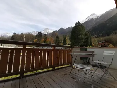a deck with a table and two chairs on it at Terra Losa - Tout Nouveau - Centre des Houches - Point de Départ et D'arrivée TMB in Les Houches