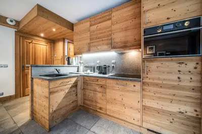 a kitchen with wooden cabinets and a sink and a microwave at Apartment Valvisons Les Houches Chamonix - by EMERALD STAY in Les Houches