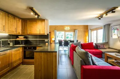 a living room with a red couch and a kitchen at Delys - Renovated - Beside Park - Climbing wall - Hikes - Mont-Blanc views in Les Houches