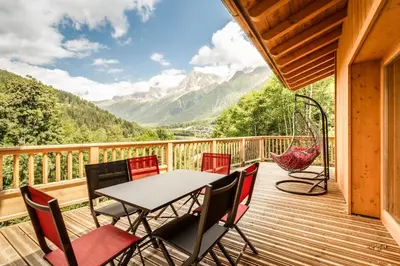 a deck with a table and chairs and a hammock at Delys - Renovated - Beside Park - Climbing wall - Hikes - Mont-Blanc views in Les Houches