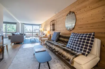 a living room with a couch and a wooden wall at Apartment Cortirion Megeve - by EMERALD STAY in Megève