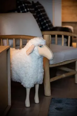 a toy sheep standing in front of a chair at Apartment Cortirion Megeve - by EMERALD STAY in Megève