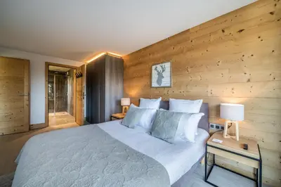a bedroom with a large bed and a wooden wall at Apartment Cortirion Megeve - by EMERALD STAY in Megève