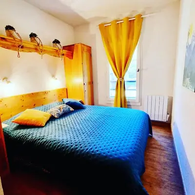 a bedroom with a blue bed and a window at Appartement avec piscine & jardin pied de la télécabine in Saint-Gervais-les-Bains