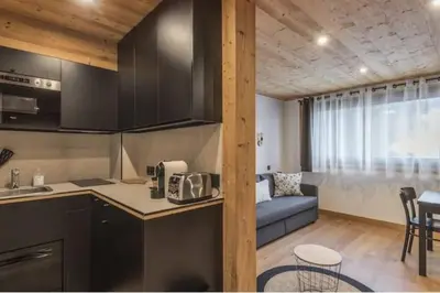 a kitchen and a living room with a couch at Charmant T2 Megève, 10 min à pied du centre in Megève