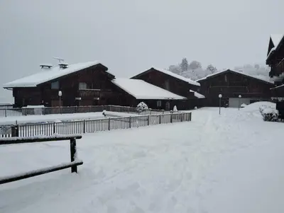a snow covered yard in front of some wooden buildings at Saint-Gervais, appart cosy, piscine & pied des pistes in Saint-Gervais-les-Bains