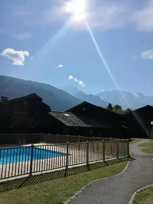 a fence next to a pool with mountains in the background at Saint-Gervais, appart cosy, piscine & pied des pistes in Saint-Gervais-les-Bains