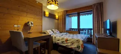 a bedroom with a bed and a desk and a television at Lune D'Argent Appartement avec vue sur la montagne in Megève