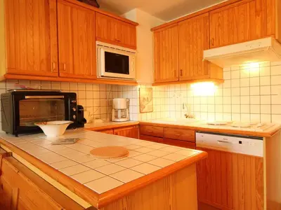 a kitchen with wooden cabinets and a counter top at Studio cosy 4 pers avec parking, lave-vaisselle, balcon, proche des pistes et commerces - FR-1-572-56 in Arâches-la-Frasse