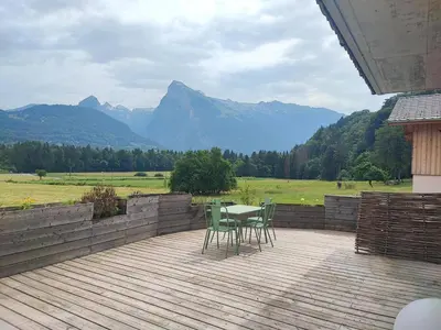 a table and chairs on a deck with mountains in the background at Appartement calme 2 chambres avec terrasse à Samoëns - FR-1-642-77 in Samoëns