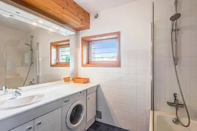 a bathroom with a sink and a washing machine at Appartement Stenoga - Welkeys in Megève