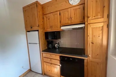 a small kitchen with wooden cabinets and a refrigerator at Appartement Stenoga - Welkeys in Megève