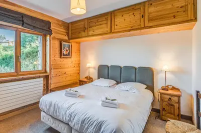 a bedroom with a large bed in a room with wooden walls at Appartement Stenoga - Welkeys in Megève
