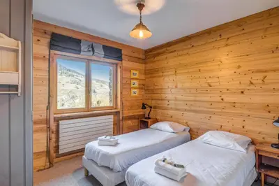 two beds in a room with wooden walls at Appartement Stenoga - Welkeys in Megève
