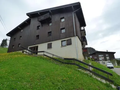 a large building on top of a grassy hill at Studio + Alcôve 4 Couchages, Balcon, Parking, Skis - Proche Rochebrune, Megève - FR-1-597-168 in Megève