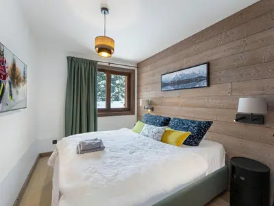 a door leading into a living room with a chair at Appartement neuf avec terrasse, 2 chambres près des pistes, sauna, hammam, salle de sport, parking - FR-1-569-57 in Megève