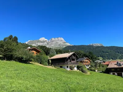 a group of houses on a hill with a mountain in the background at Chalet à Cordon face à la chaîne du Mont Blanc in Cordon