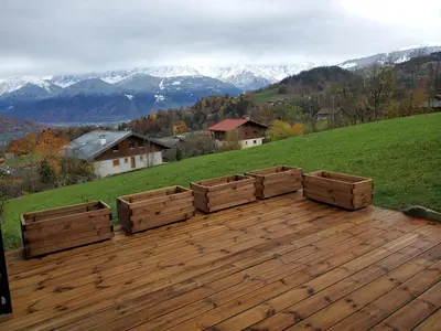 a wooden deck with wooden boxes on top of a hill at Chalet à Cordon face à la chaîne du Mont Blanc in Cordon