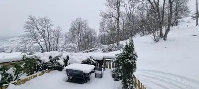 a snow covered yard with a house and trees at Logement à Megève avec Jardin in Megève