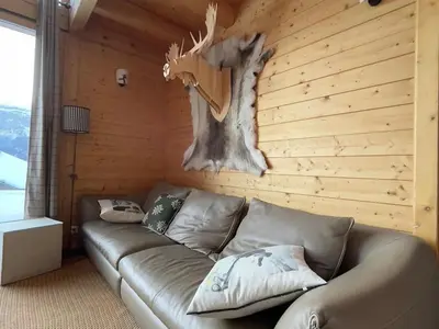 a living room with a leather couch and a deer head on the wall at Chalet indépendant 8 pers, déco moderne, proche centre et remontées, terrasse sud-ouest - FR-1-572-32 in Arâches-la-Frasse