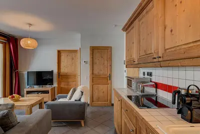 a kitchen with wooden cabinets and a living room at Apartment le Paradis 1 - Alpes Travel - Central Chamonix (sleeps 4) in Chamonix-Mont-Blanc